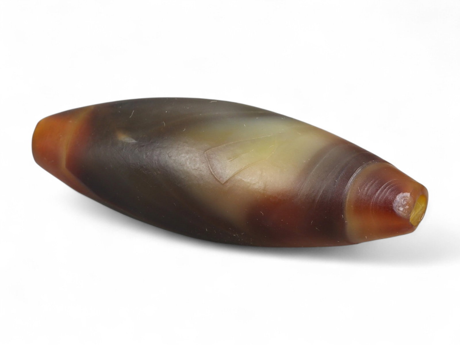 Ancient Tibetan Himalayan Banded Agate Dzi Bead, c. 9th-14th Century CE, 4.5cm: This ancient Tibetan Dzi bead, measuring 2.6 cm, is carved from richly banded agate, its surface revealing bold layers of deep red, amber, and ivory-white. Its elongated cylindrical form, tapering at 