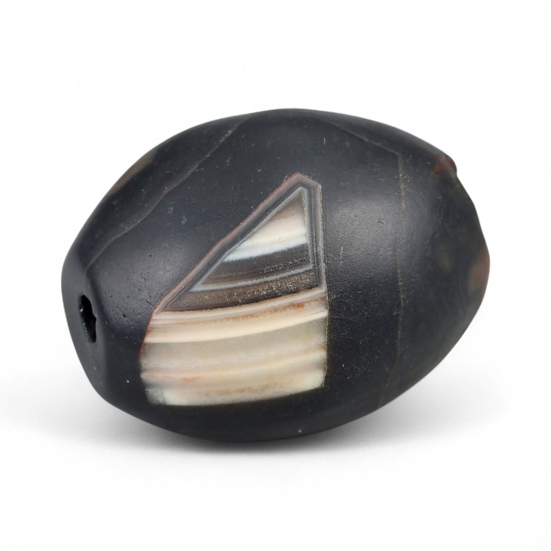 Antique Himalayan Banded Agate Amulet Bead, c. 15th-17th Century, 3cm: This bead, carved from banded agate with smoky brown and gray tones, dates to the Himalayan region between the 15th and 17th centuries. Its elongated oval form, shows concentric layering, a characteri