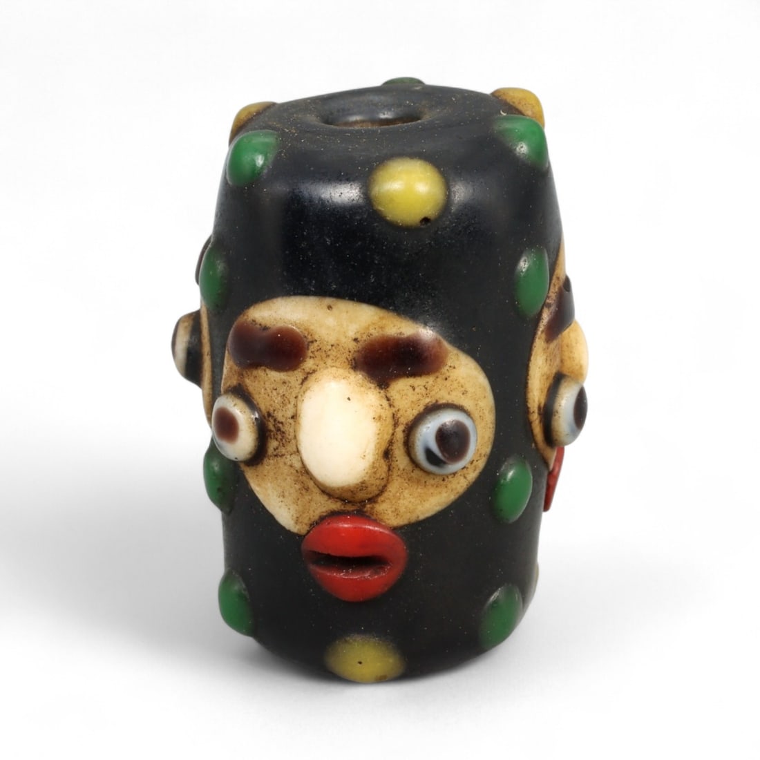 Antique Phoenician Style Multicolored Glass Face Bead, c. 19th-20th Century, 2.5cm: This vibrant antique bead is crafted in the distinctive Phoenician style, featuring a molded human face with applied multicolored details. Its bold design includes protruding eyes, a defined nose, and