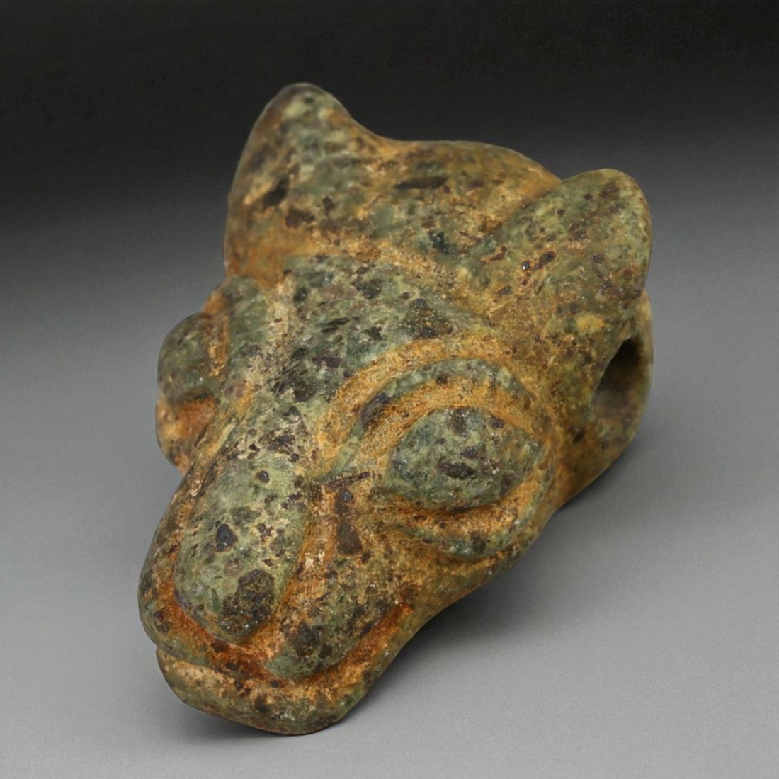 Ancient Sasanian Persian Green Serpentine Feline-Head Bead, c. 3rd-6th Century CE (1.9 cm): This powerful bead, carved in the form of a feline head from mottled green serpentine, originates from the Sasanian Persian Empire - an era renowned for its fusion of regal symbolism and exquisite lap