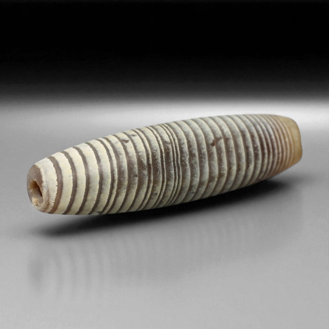 Ancient Persian Banded Agate Bead, Parthian-Roman Period c. 1st-3rd Century CE, 2cm, 0.9g: This elegant banded agate bead, originates from Persia during the Parthian-Roman cultural horizon of the 1st-3rd century CE. Agate, with its natural striations and layered beauty, was one of the most