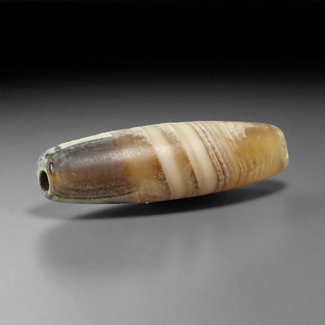 Ancient Persian Banded Agate Bead, Parthian-Roman Period c. 1st-3rd Century CE, 2cm, 0.9g: This elegant banded agate bead, originates from Persia during the Parthian-Roman cultural horizon of the 1st-3rd century CE. Agate, with its natural striations and layered beauty, was one of the most