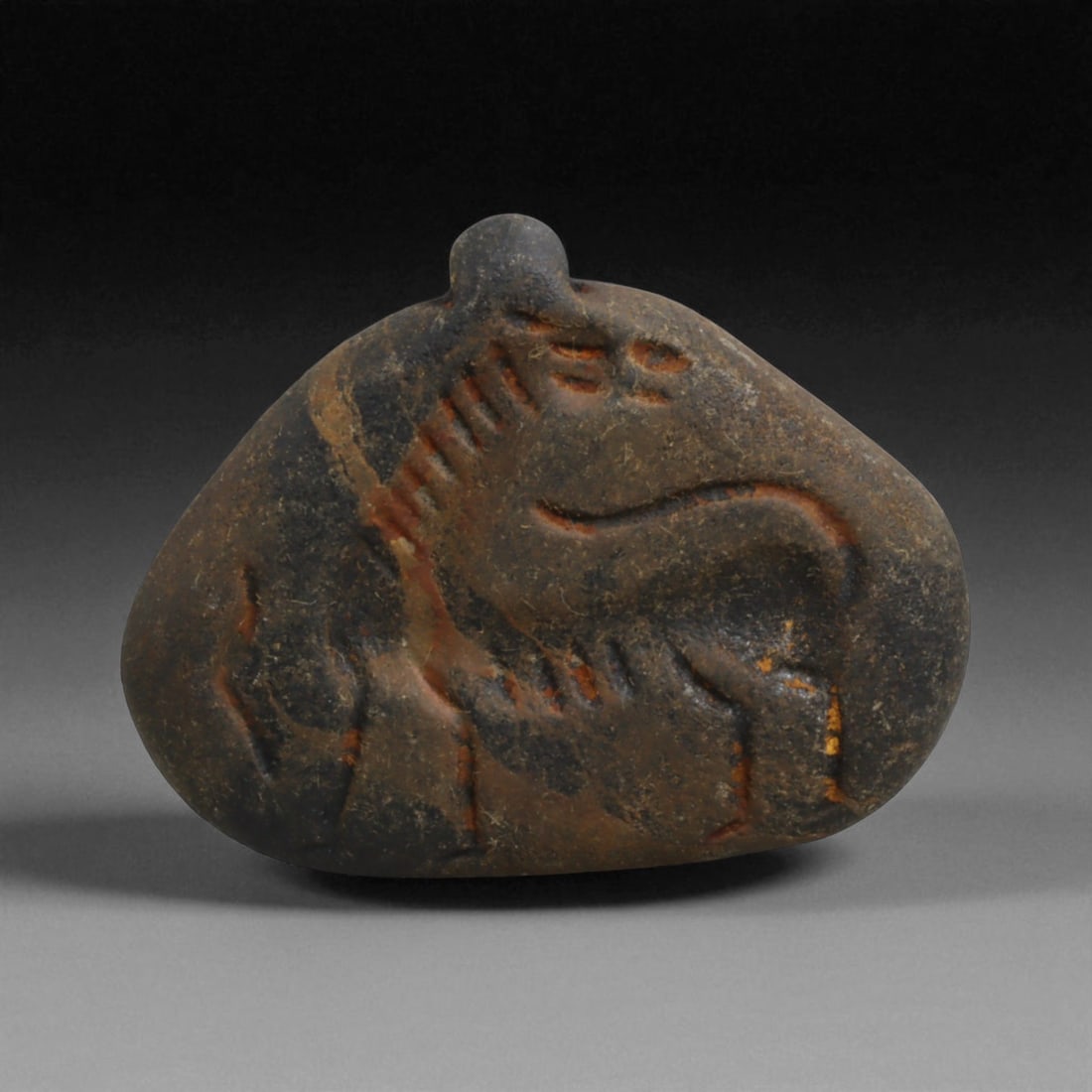 Ancient Neo-Babylonian Steatite Gazelle Motif Amulet Pendant, c. 7th-6th Century BCE, 4.2cm, 15g: This pendant, carved from dark steatite, dates to the Neo-Babylonian period, c. 7th-6th century BCE. Pierced at the top for suspension, it was designed as a personal amulet to be worn close to the bod