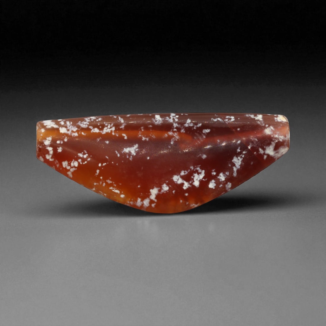 Ancient Parthian-Roman Carnelian Bow Amulet Bead, c. 1st-3rd Century CE, 4.6cm, 7g: This finely carved bow-shaped bead, is fashioned from carnelian agate with natural inclusions that lend it a mottled red-and-white surface of striking beauty. Originating from the Parthian-Roman perio