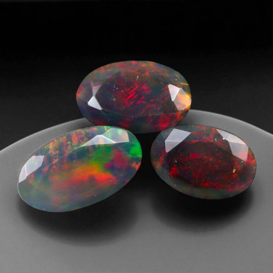 5.46 Carats Dark Fire Opal Faceted Selection - Natural Ethiopian Stones: This dramatic selection of dark Ethiopian opal faceted exhibits a captivating interplay of color set against deep, smoky body tones. Flashes of crimson, emerald, and violet ignite within the stones, p