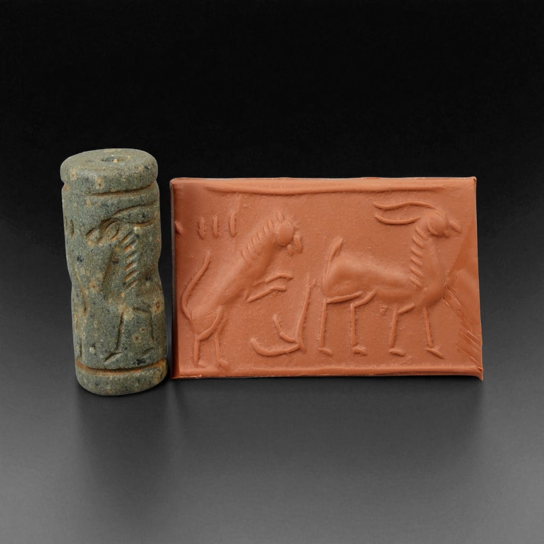 Ancient Early Dynastic Confronted Caprids Motif Chlorite Cylinder Seal, c. 2900-2350 BCE, 4.0 cm: This finely carved cylinder seal, dating to the Early Dynastic Period of Mesopotamia (circa 2900-2350 BCE), is rendered from deep green chlorite and displays a dynamic scene of two confronted caprids 