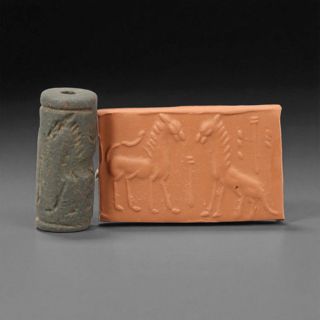 Ancient Early Dynastic Confronted Equids and Feline Motif Chlorite Cylinder Seal, c. 2900-2350 BCE,: This remarkable cylinder seal, carved from deep gray-green chlorite, dates to the Early Dynastic Period of Mesopotamia (circa 2900-2350 BCE). The composition presents two elegantly rendered equids fac