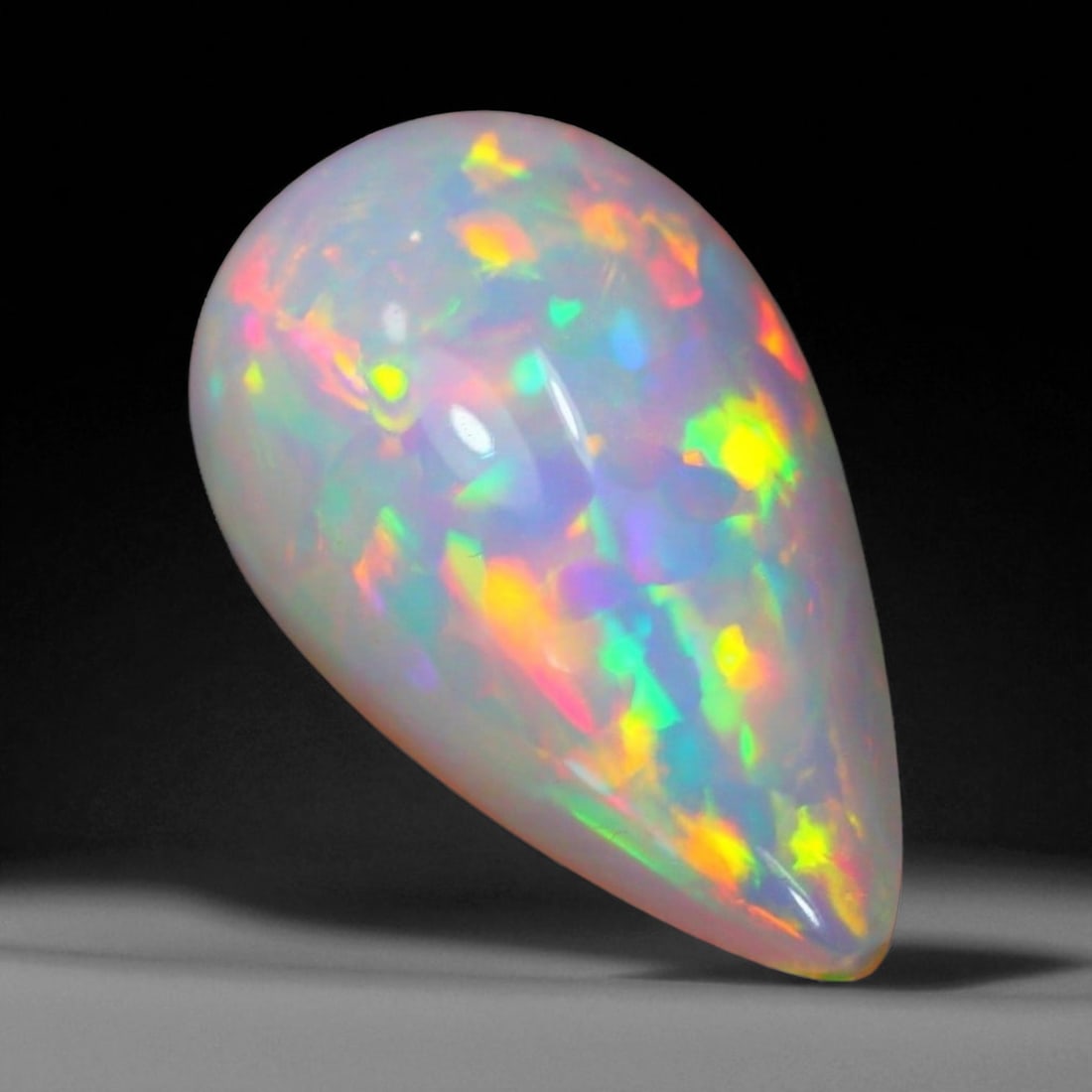 3.20 Carats Fiery Play-of-Color Welo Opal Oval Cabochon - Natural Ethiopian Stone: This mesmerizing Welo opal radiates a luminous play-of-color that dances across its translucent body in vivid flashes of red, orange, green, and violet 14.9x8.8x5.9mm. The gem's opalescent base glows 