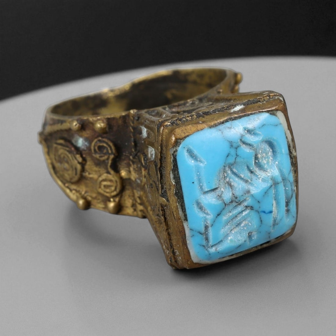 Antique Qajar Gold Gilt Intaglio Signet Ring, c. 19th-20th Century, 9 US: This substantial gilt ring, dating to the Qajar era of the 19th-20th century, embodies the regal aesthetic and cultural refinement of Persian jewelry traditions. The bezel is set with an engraved inta