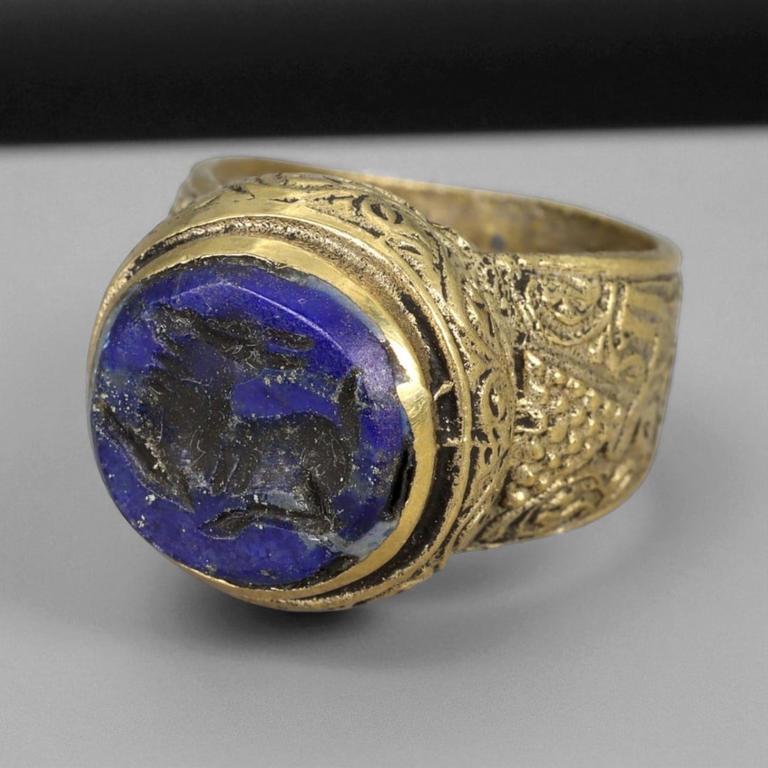 Antique Qajar Gold Gilt Intaglio Signet Ring, c. 19th-20th Century, 6.5 US: This substantial gilt ring, dating to the Qajar era of the 19th-20th century, embodies the regal aesthetic and cultural refinement of Persian jewelry traditions. The bezel is set with an engraved inta