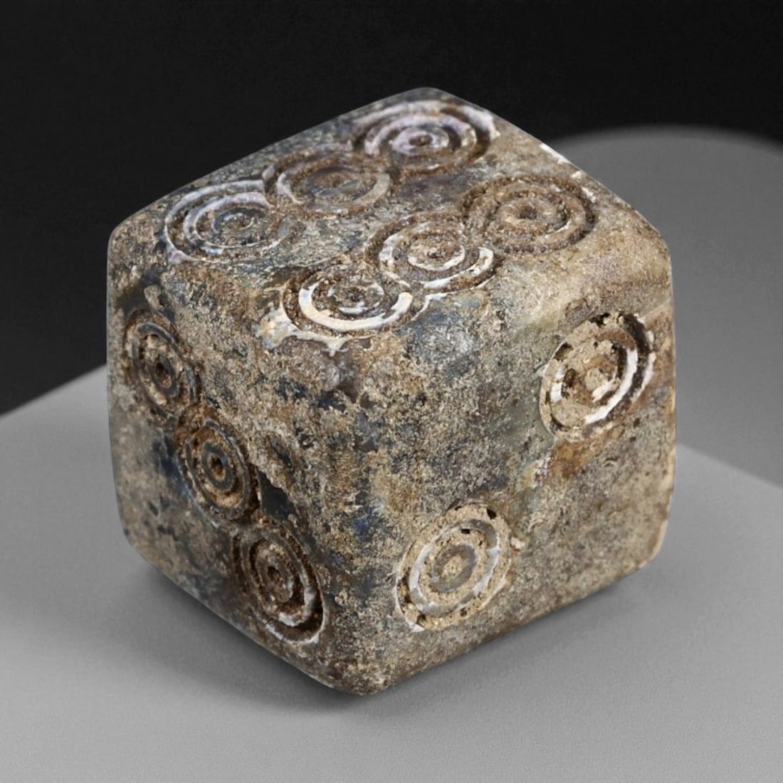 Ancient Roman Bone Dice with Ring-and-Dot Motifs, c. 1st-3rd Century CE, 1.2cm: This ancient Roman gaming die, carved from bone and measuring 1.2 cm across, dates to the 1st-3rd century CE, during the height of the Roman Empire. The cube is intricately engraved with the tradition