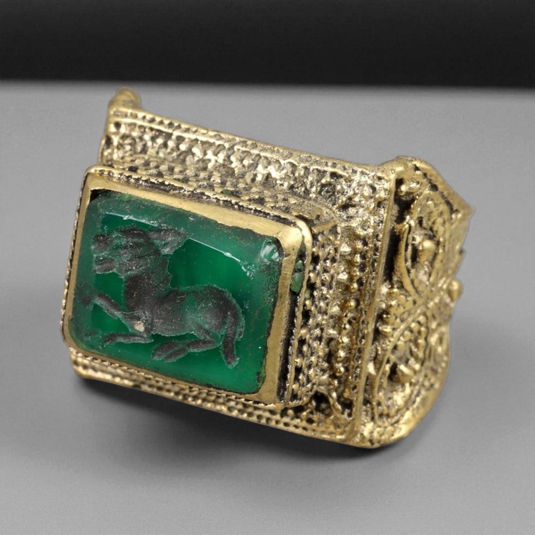 Antique Qajar Gold Gilt Intaglio Signet Ring, c. 19th-20th Century, 8 US: This substantial gilt ring, dating to the Qajar era of the 19th-20th century, embodies the regal aesthetic and cultural refinement of Persian jewelry traditions. The bezel is set with an engraved inta