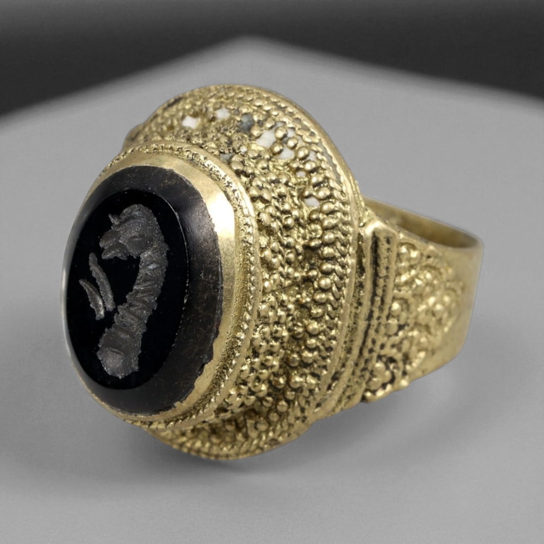 Antique Qajar Gold Gilt Intaglio Signet Ring, c. 19th-20th Century, 8 US: This substantial gilt ring, dating to the Qajar era of the 19th-20th century, embodies the regal aesthetic and cultural refinement of Persian jewelry traditions. The bezel is set with an engraved inta
