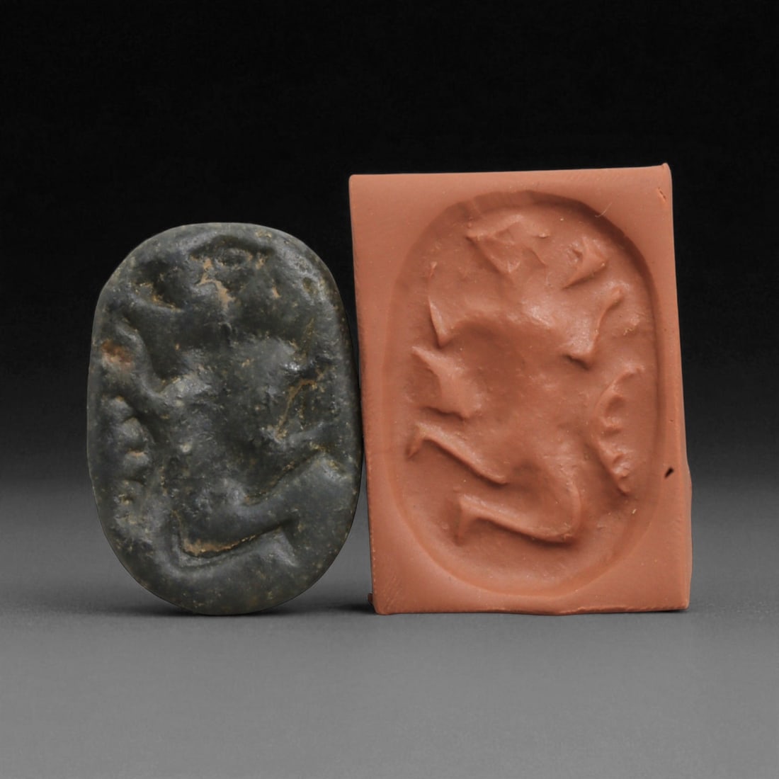 Ancient Kassite Anthropomorphic Stamp Seal in Dark Stone, c. 1500-1150 BCE, 3.1cm: This intriguing oval stamp seal originates from the Kassite Period of Mesopotamia (c. 1595-1155 BCE), an era that succeeded the Old Babylonian Empire and fostered a distinctive artistic vocabulary ric