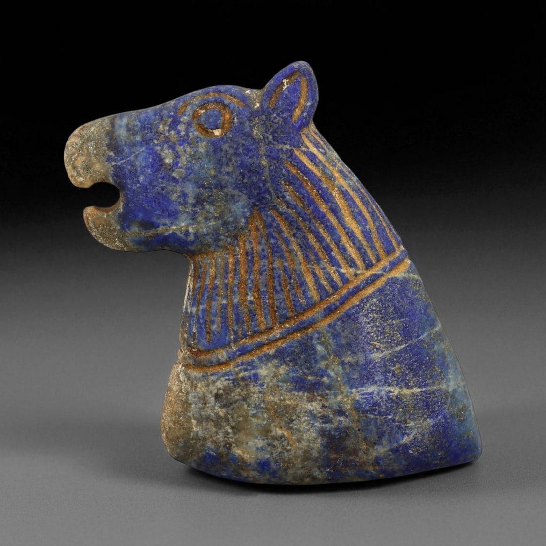 Ancient Bactrian Lapis Lazuli Lion-Head Plaque, c. 2nd-1st Millennium BCE, H 7cm: This magnificent lapis lazuli plaque, carved in the form of a roaring lion's head, originates from ancient Bactria, circa 2nd-1st millennium BCE. Bold yet refined, the plaque exemplifies the distincti