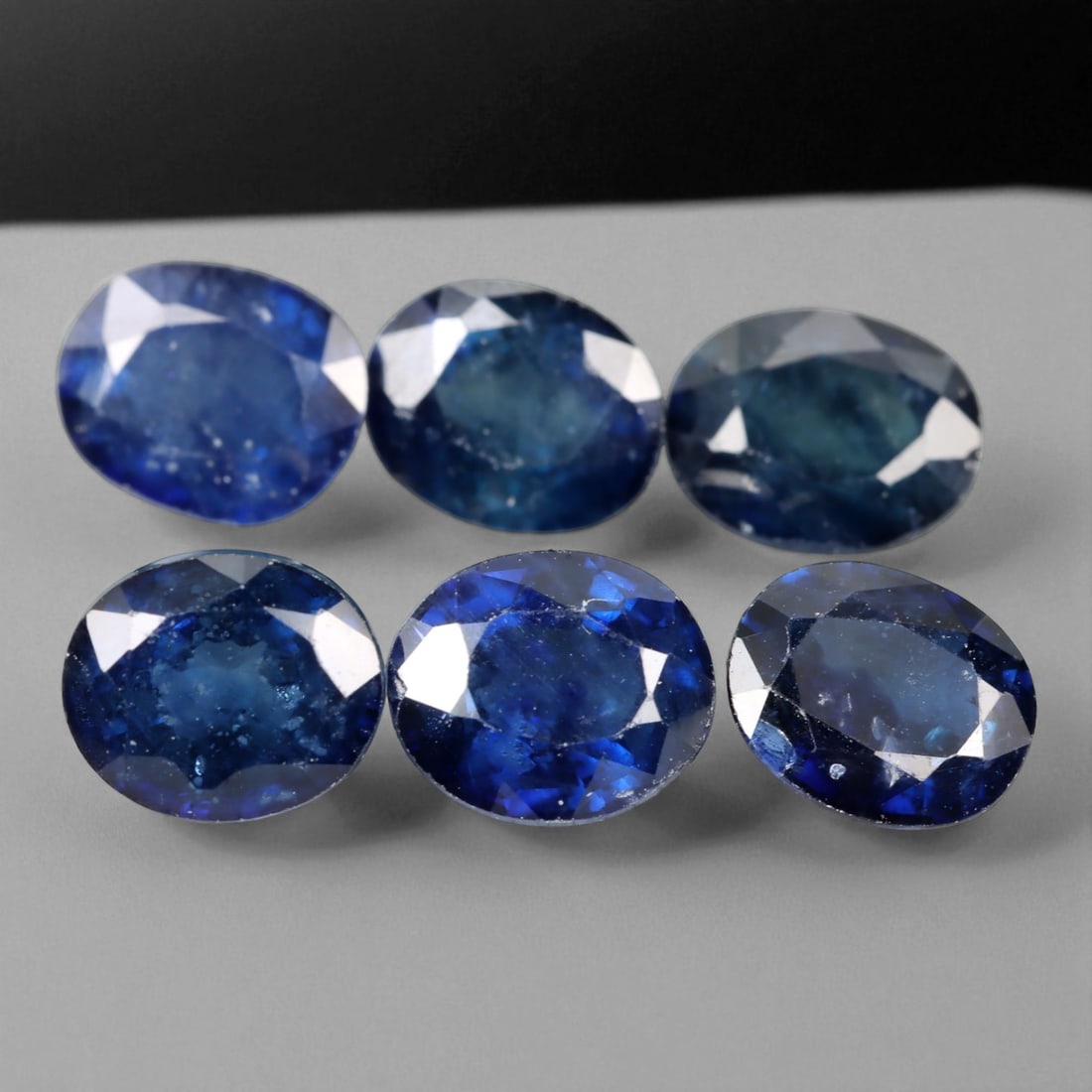 6.41 Carats Royal Blue Sapphire Oval Lot - Natural Ceylon Stones: This captivating lot of oval-cut sapphires exhibits a deep royal blue color, rich and even, with flashes of lighter brilliance across the facets. Each stone, measuring approximately 5.9x4.9x3.5mm, is 