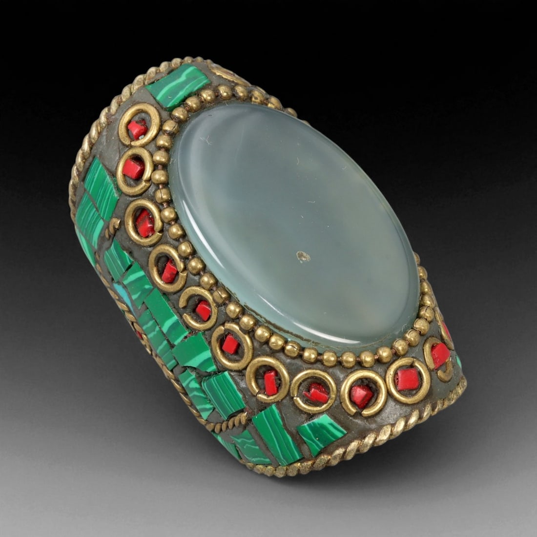 Vintage Himalayan Tribal Green Stone Coral Brass Ring, 20th Century, US Size 8: This impressive vintage Himalayan ring reflects the powerful aesthetic and sacred symbolism of traditional highland jewelry. Crafted from brass, it features a smooth, domed green stone cabochon at its