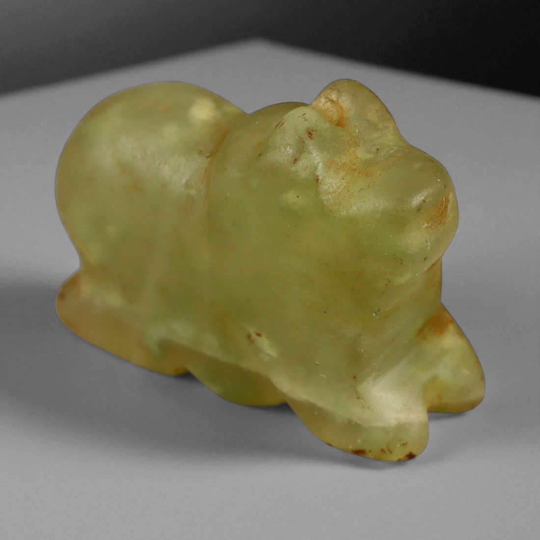 Ancient Mesopotamian Lion Chalcedony Amulet, c. 2nd Millennium BCE 2cm: This compact amulet, sculpted in translucent pale green chalcedony, represents a lion in a stylized crouching pose and dates to the Mesopotamian region during the 2nd millennium BCE. The lion, a recur
