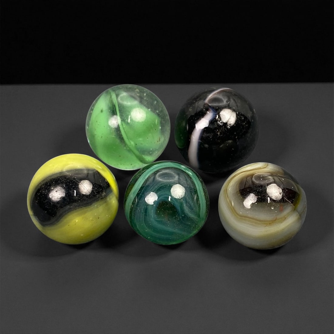 Vintage Glass Marbles Lot, Mid-20th Century, 1.4-1.6cm: This charming lot of vintage glass marbles, dating from the mid-20th century, reflects the artistry and playfulness of early handmade and molded glass craftsmanship. These marbles were produced during