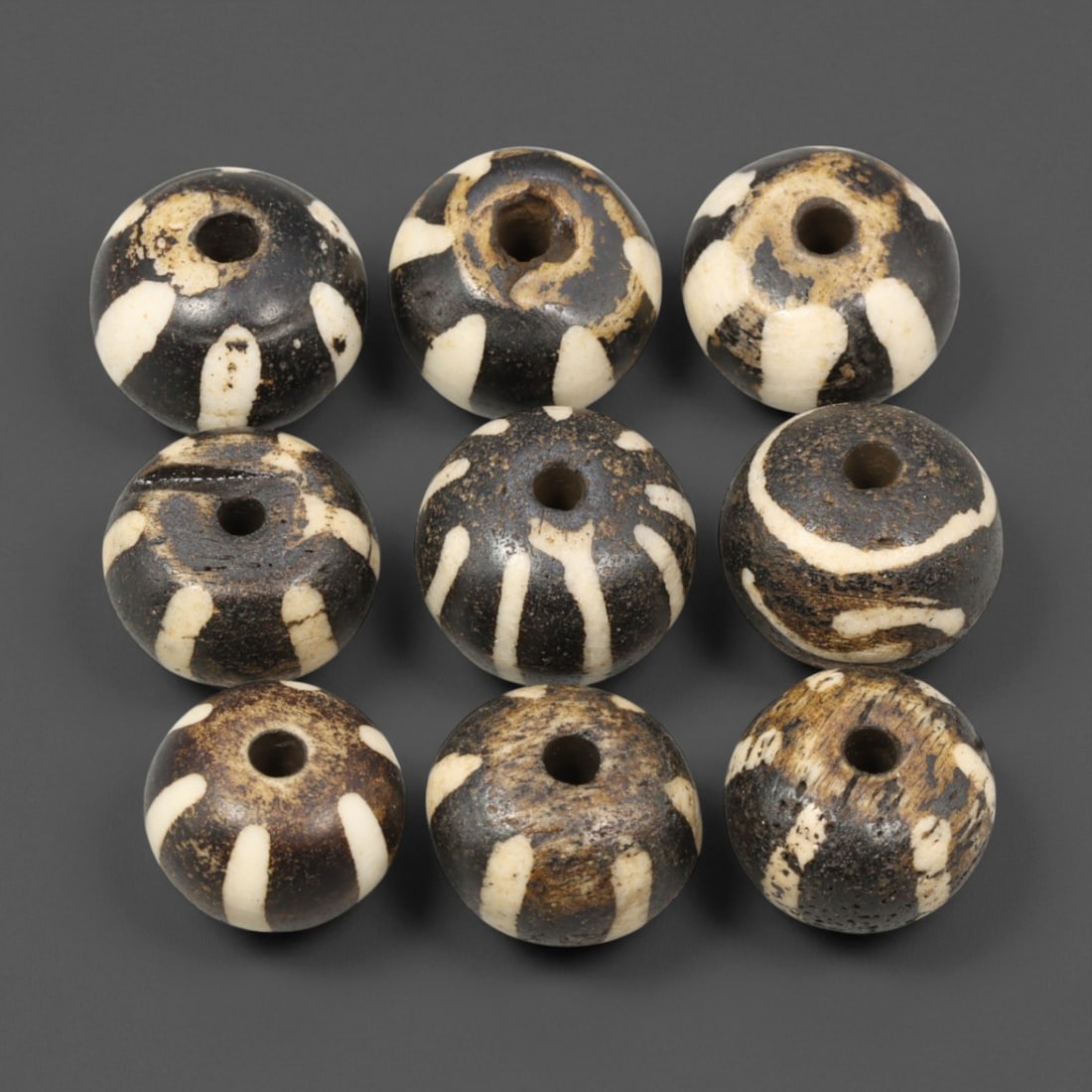 Antique Burmese Pumtek Beads, c. 19th-Early 20th Century, 1.2-1.4cm: This fine set of antique Pumtek beads originates from Burma (modern-day Myanmar), dating to the 19th-early 20th century. Crafted from fossilized palm wood, these beads feature the iconic radiating str