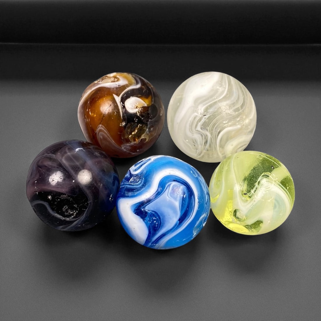 Vintage Glass Marbles Lot, Mid-20th Century, 1.6-1.8cm: This charming lot of vintage glass marbles, dating from the mid-20th century, reflects the artistry and playfulness of early handmade and molded glass craftsmanship. These marbles were produced during