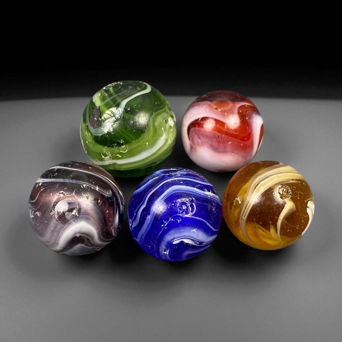 Vintage Glass Marbles Lot, Mid-20th Century, 1.7-1.9cm: This charming lot of vintage glass marbles, dating from the mid-20th century, reflects the artistry and playfulness of early handmade and molded glass craftsmanship. These marbles were produced during
