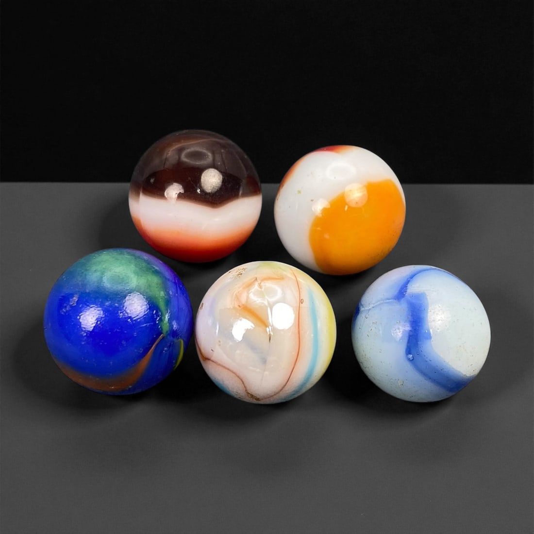 Vintage Glass Marbles Lot, Mid-20th Century, 1.5-1.6cm: This charming lot of vintage glass marbles, dating from the mid-20th century, reflects the artistry and playfulness of early handmade and molded glass craftsmanship. These marbles were produced during
