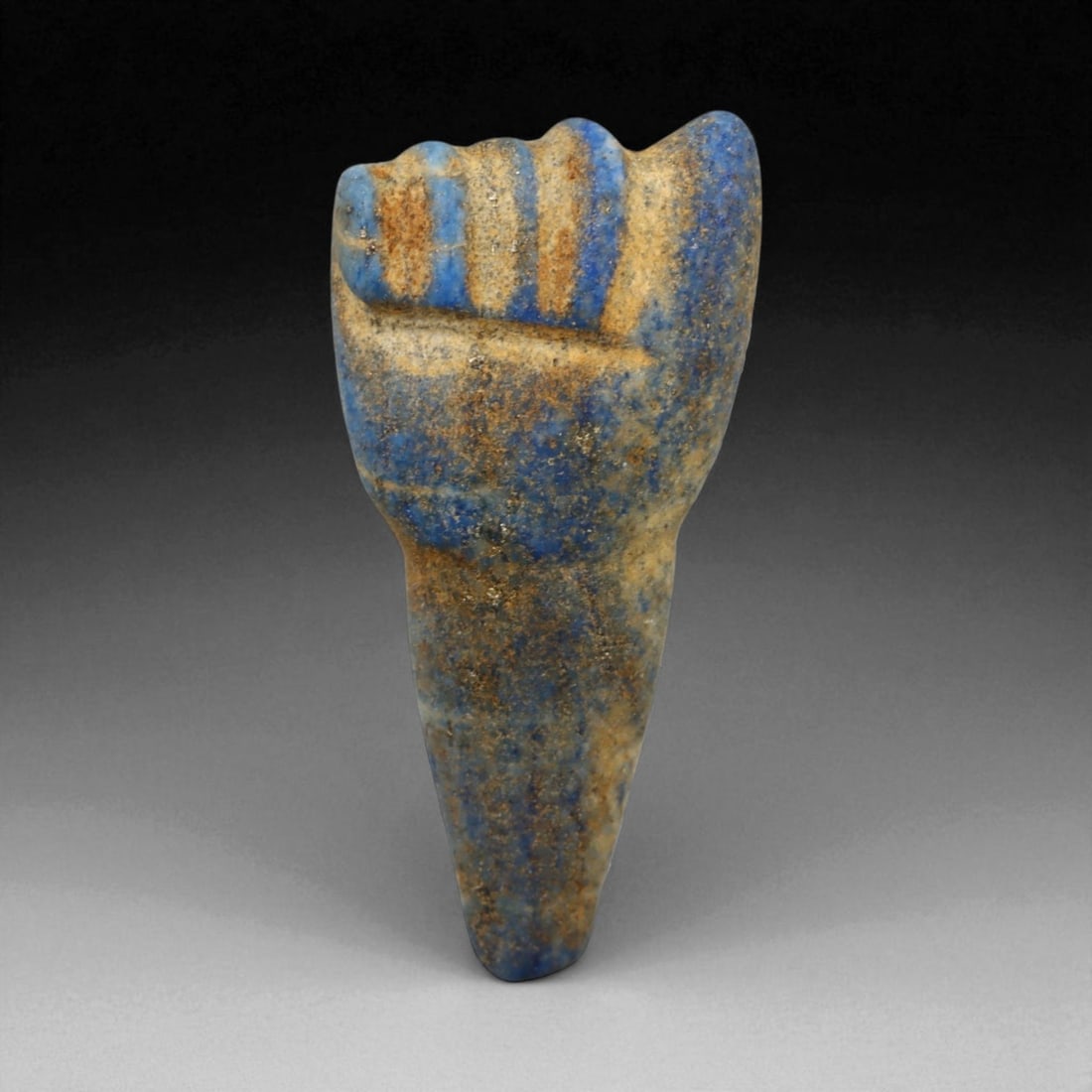Ancient Egyptian Lapis Lazuli Fist Amulet, c. 19th-21st Dynasty, New Kingdom, 25 mm: This striking lapis lazuli amulet, carved in the form of a clenched fist, dates to Egypt's New Kingdom, circa 13th-11th centuries BCE. The clenched hand was a powerful symbol of physical and spiritual