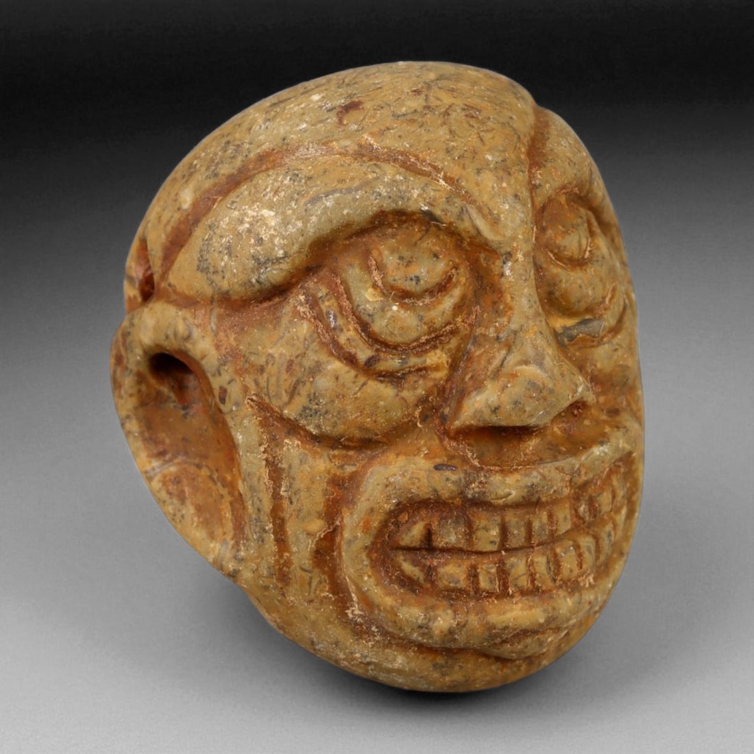 Ancient Chinese Tang Dynasty Guardian Head Amulet, c. 7th-9th Century CE, 3.8cm: This vividly expressive stone head amulet, measuring 3.8 centimeters in height, dates to the Tang Dynasty period of China, circa 7th-9th century CE. The bold features-arched brows, bulging eyes, and a