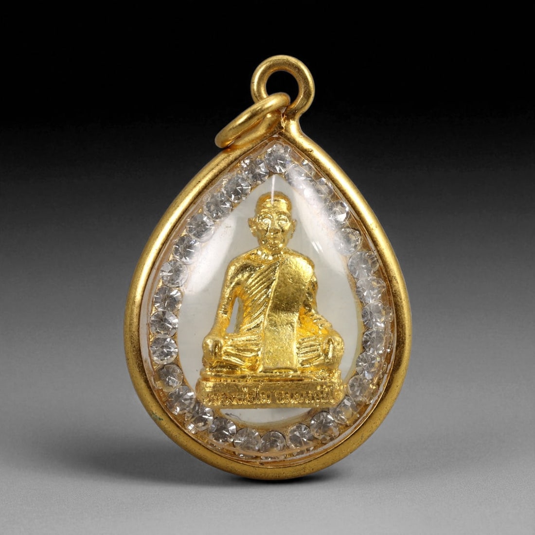 Thai Temple Gilt Buddhist Amulet in Ornate Gold-Tone Frame, 3cm: This beautifully crafted gilt Buddhist amulet is enclosed within an intricately designed gold-tone frame, combining sacred symbolism with refined artistry. The detailed relief and lustrous finish refl