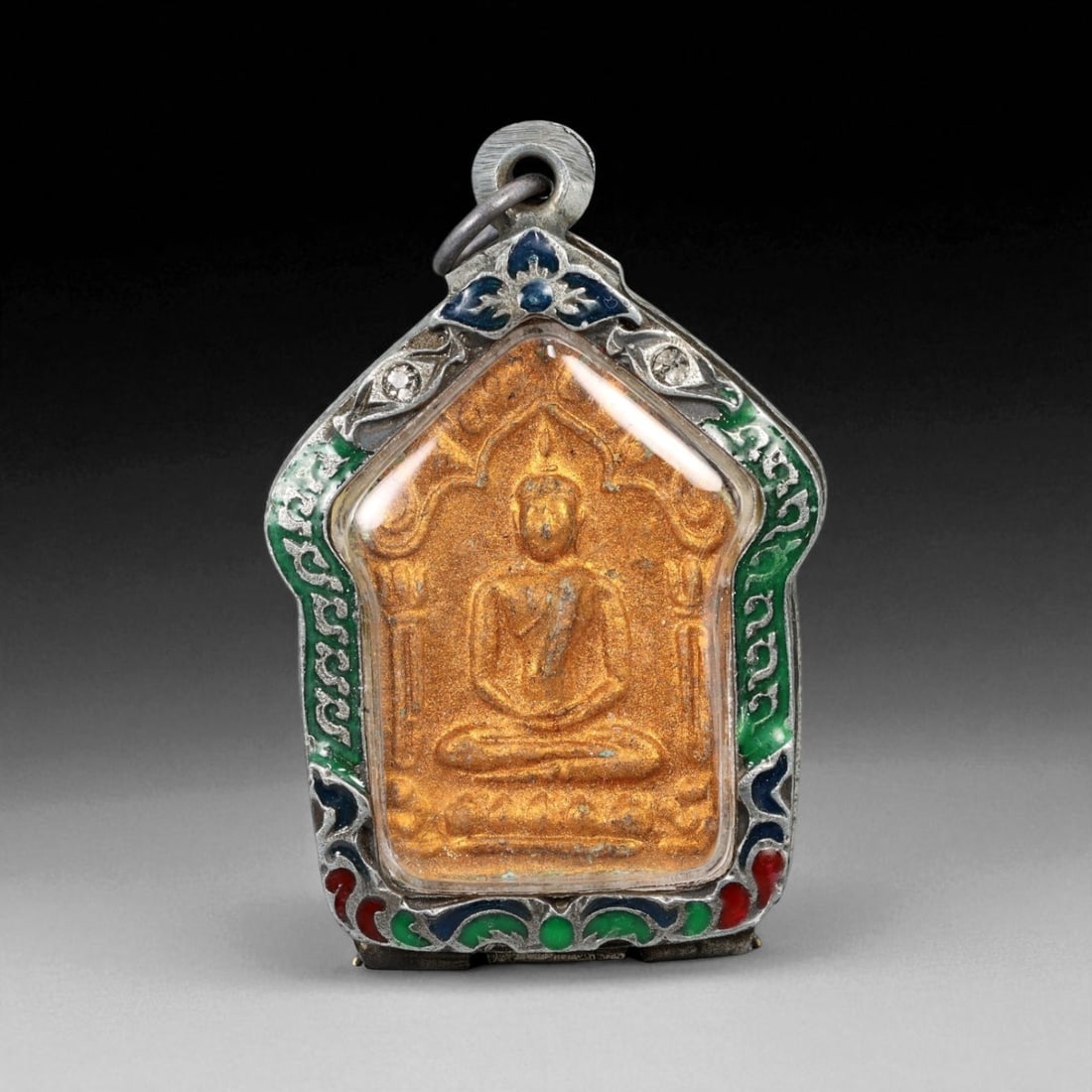 Antique Thai Rattanakosin Buddha Amulet in Enameled Silver Case, c. 19th-20th Century CE, 43g: This finely preserved Thai Buddha amulet, dating to the Rattanakosin period of the 19th to 20th century CE, presents a powerful symbol of serenity, protection, and spiritual grace. The image of the Bu