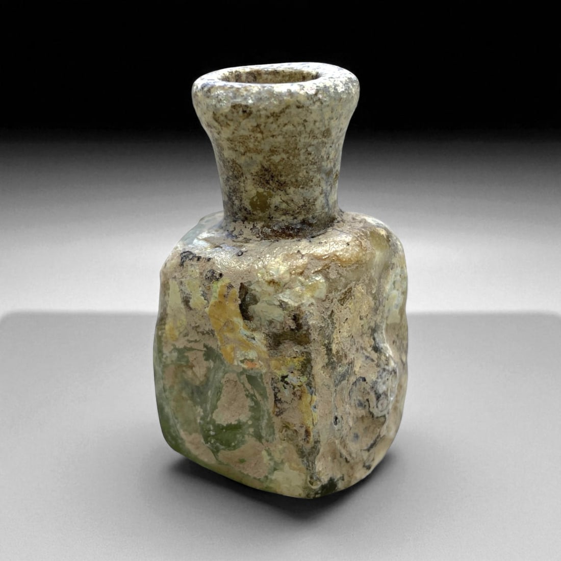 Ancient Roman Pale Green Glass Square Bottle, c. 2nd-4th Century CE, 5cm, 32g: This petite Roman glass bottle, dating to the Imperial period (c. 2nd-4th century CE), reflects the elegant simplicity and technical sophistication characteristic of Roman daily glassware. Mold-blown 