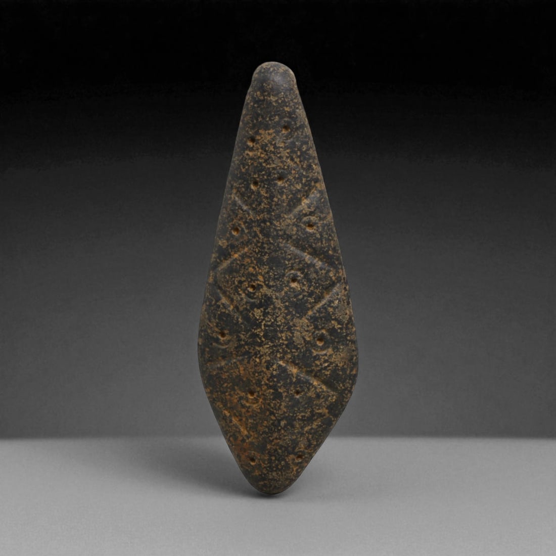 Ancient Indus Valley Steatite Concentric Circle Amulet Pendant, c. 2500-2000 BCE, 5.6cm, 12g: This amulet pendant, carved from dark steatite, originates from the Indus Valley Civilization, c. 2500-2000 BCE. Its elongated, kite-shaped body is engraved with a series of concentric circles, a hall