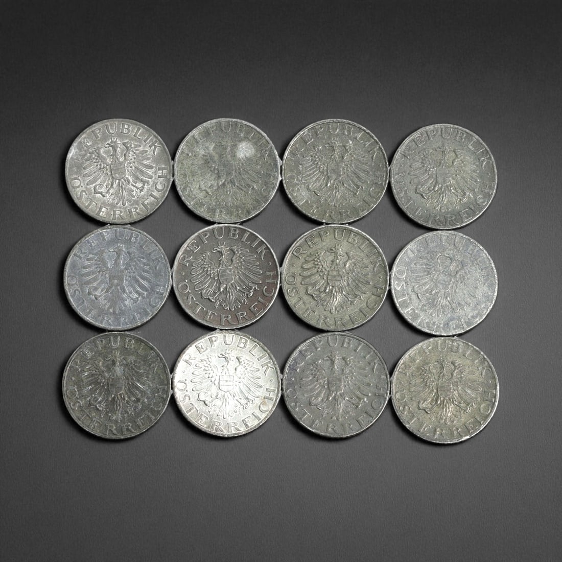 AUSTRIA: Republican Emblem - National Arms 5 Groschen Coin, 1953-1990, 20mm (Lot of 12): Uniting nearly four decades of postwar Austrian coinage, this 12-coin lot of 5 Groschen pieces embodies both institutional continuity and the quiet symbolism of national resilience. Each obverse featu
