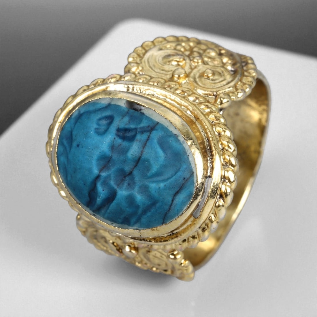 Antique Qajar Gold Gilt Intaglio Signet Ring, c. 19th-20th Century, 9 US, 13g: This substantial gilt ring, dating to the Qajar era of the 19th-20th century, embodies the regal aesthetic and cultural refinement of Persian jewelry traditions. The bezel is set with an engraved inta