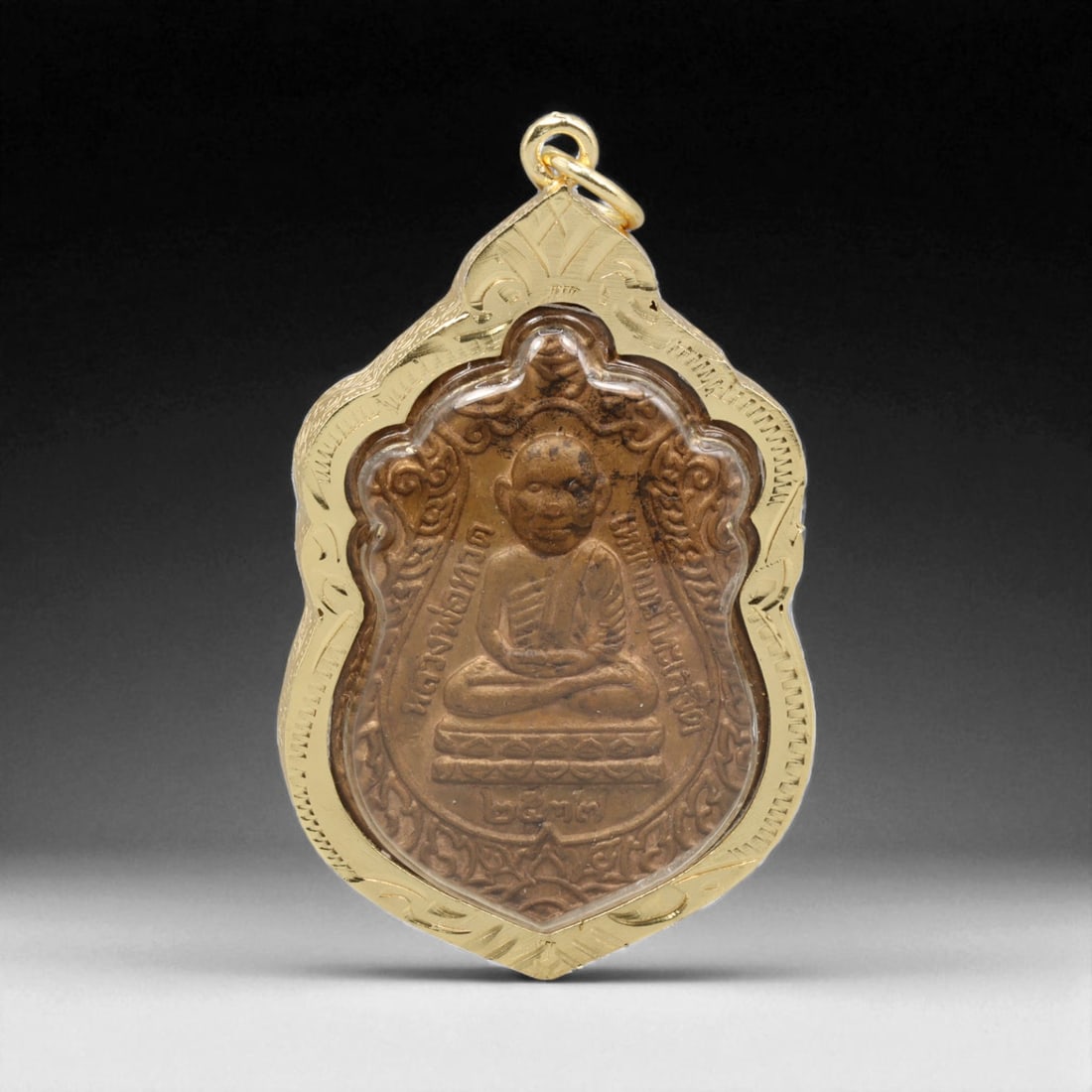 Thai Temple Gilt Buddhist Amulet in Ornate Gold-Tone Frame, 5.5cm: This beautifully crafted gilt Buddhist amulet is enclosed within an intricately designed gold-tone frame, combining sacred symbolism with refined artistry. The detailed relief and lustrous finish refl
