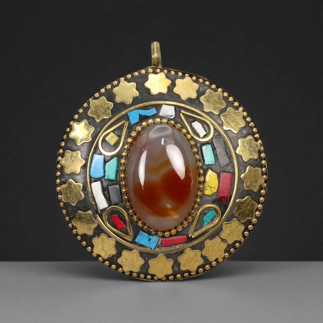 Vintage Himalayan Tribal Mosaic Agate Brass Pendant, 20th Century, 6cm: This striking round pendant captures the vibrant artistry of 20th-century Himalayan tribal jewelry, blending spiritual symbolism with masterful craftsmanship. At its center rests a polished blue bande
