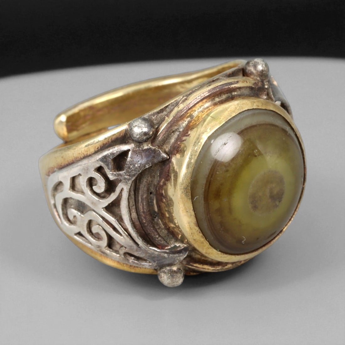 Vintage Himalayan Luk Mik Goat Eye Dzi Silver Gilt Ring, 20th Century: This powerful Himalayan ring, crafted in the 20th century, is set with a Luk Mik "Goat Eye" dzi stone cabochon in a wide silver gilt band with silver decorative accents. The dzi stone displays its cha