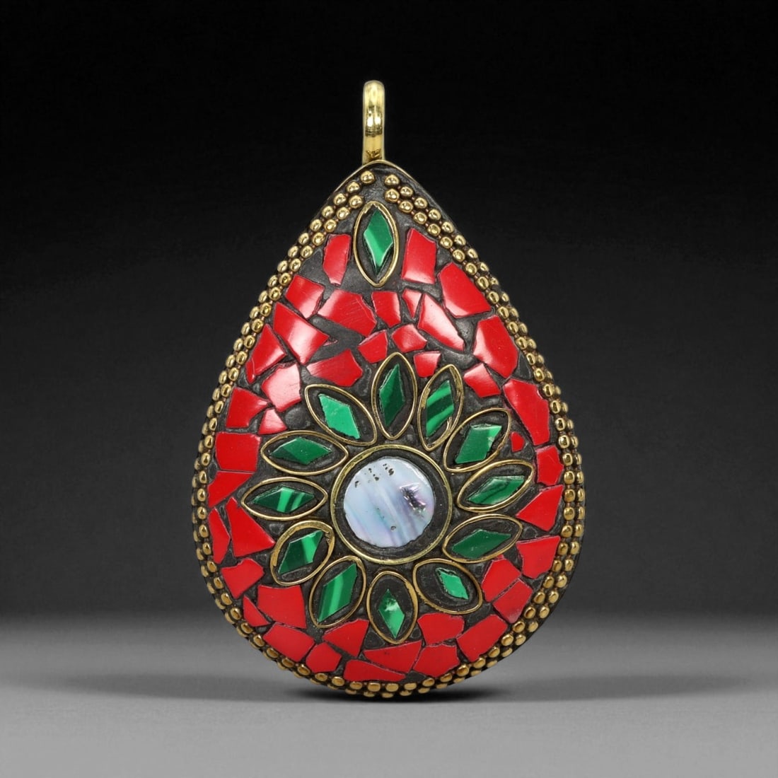 Vintage Himalayan Tribal Coral, Malachite, and Mother-of-Pearl Brass Teardrop Pendant, 20th Century,: This radiant teardrop-shaped pendant exemplifies the exquisite artistry and vibrant symbolism of Himalayan tribal jewelry. Its bold surface is adorned with a mosaic of deep red coral and rich green ma