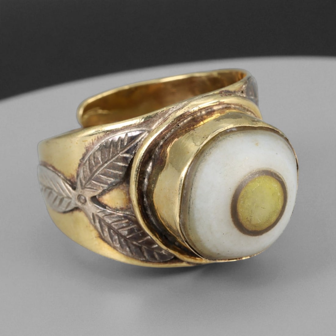 Vintage Himalayan Luk Mik Goat Eye Dzi Silver Gilt Ring, 20th Century: This powerful Himalayan ring, crafted in the 20th century, is set with a Luk Mik "Goat Eye" dzi stone cabochon in a wide silver gilt band with silver decorative accents. The dzi stone displays its cha