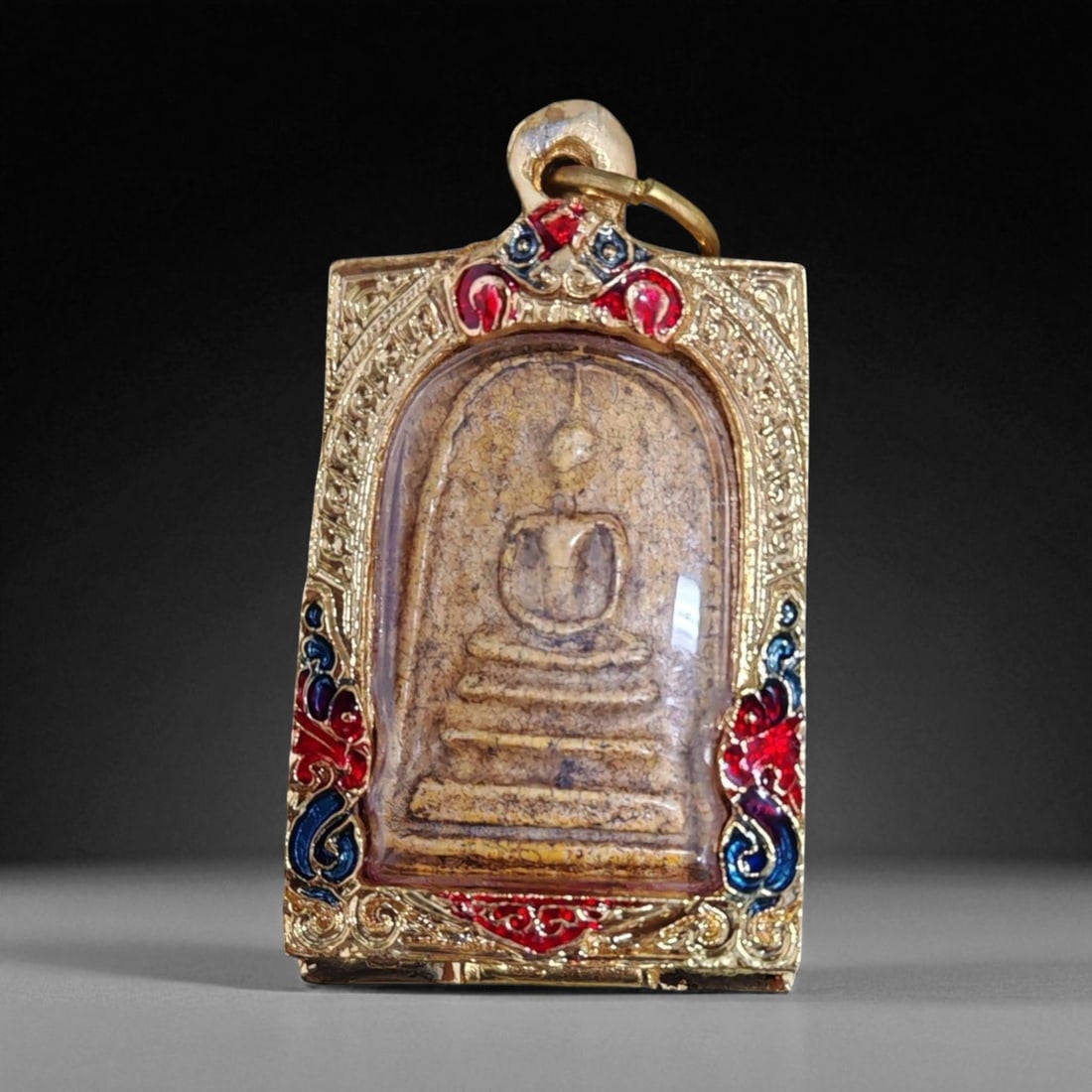 Antique Thai Rattanakosin Buddha Image Clay Amulet in Gilt Enamel Case, c. 19th-20th Century,: This antique Thai amulet presents the classic form of the seated Buddha in meditation within a rounded arched niche. Crafted from clay with natural age crackling, it belongs to the Rattanakosin Kingdo