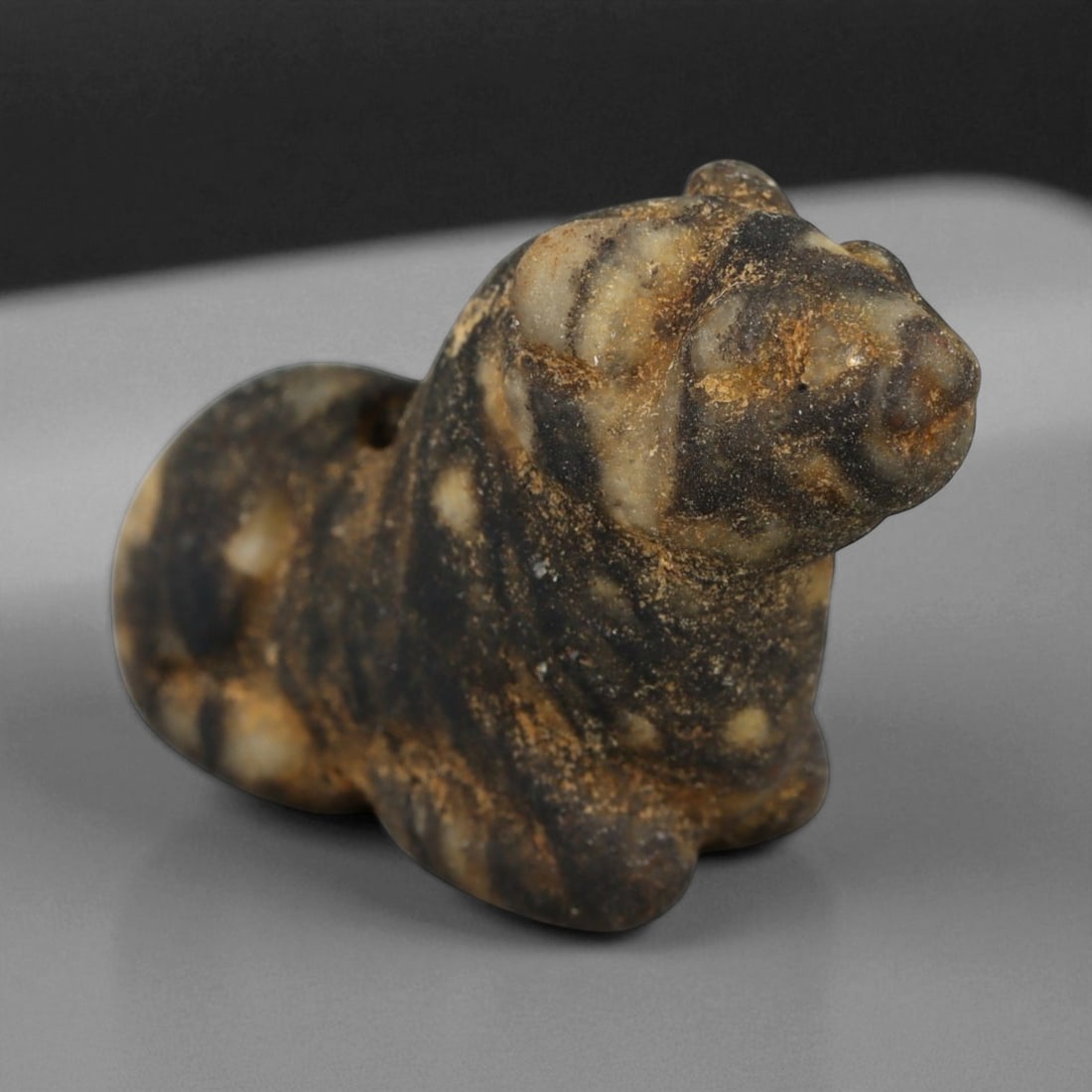 Ancient Egyptian Banded Stone Feline Amulet, New Kingdom, c. 16th-11th Century BCE, 2.4cm: This compact and expressive feline amulet, carved from a naturally banded stone, dates to Egypt's New Kingdom period (c. 16th-11th century BCE). Its form, both alert and composed, embodies the feline'