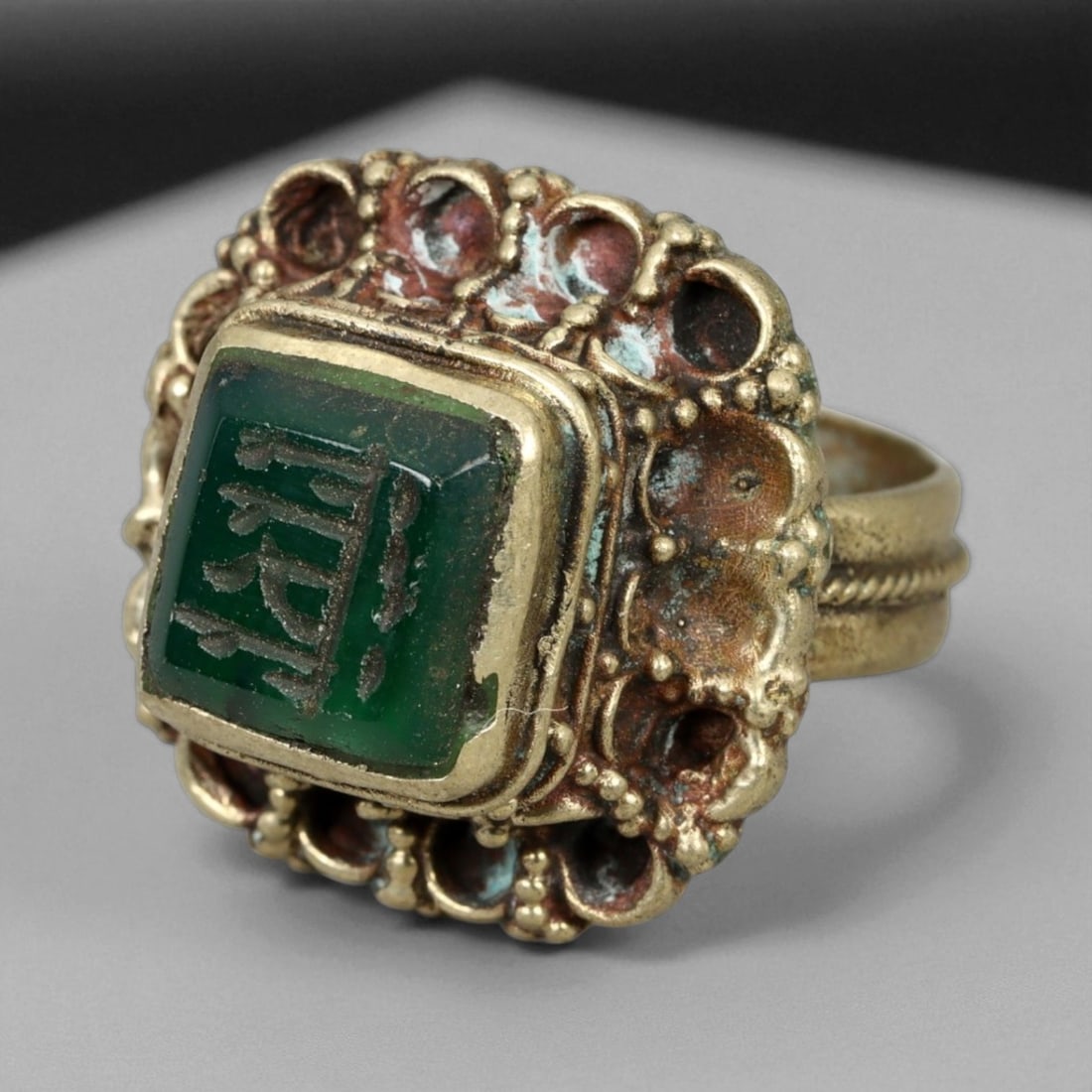 Antique Qajar Gold Gilt Intaglio Signet Ring, c. 19th-20th Century, 6.5 US: This substantial gilt ring, dating to the Qajar era of the 19th-20th century, embodies the regal aesthetic and cultural refinement of Persian jewelry traditions. The bezel is set with an engraved inta