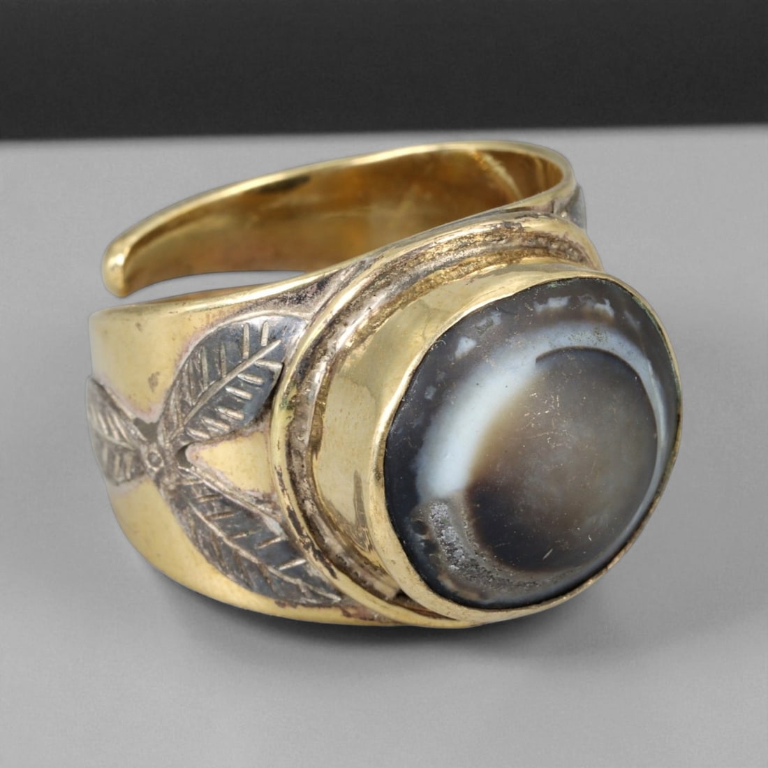 Vintage Himalayan Luk Mik Goat Eye Dzi Silver Gilt Ring, 20th Century: This powerful Himalayan ring, crafted in the 20th century, is set with a Luk Mik "Goat Eye" dzi stone cabochon in a wide silver gilt band with silver decorative accents. The dzi stone displays its cha