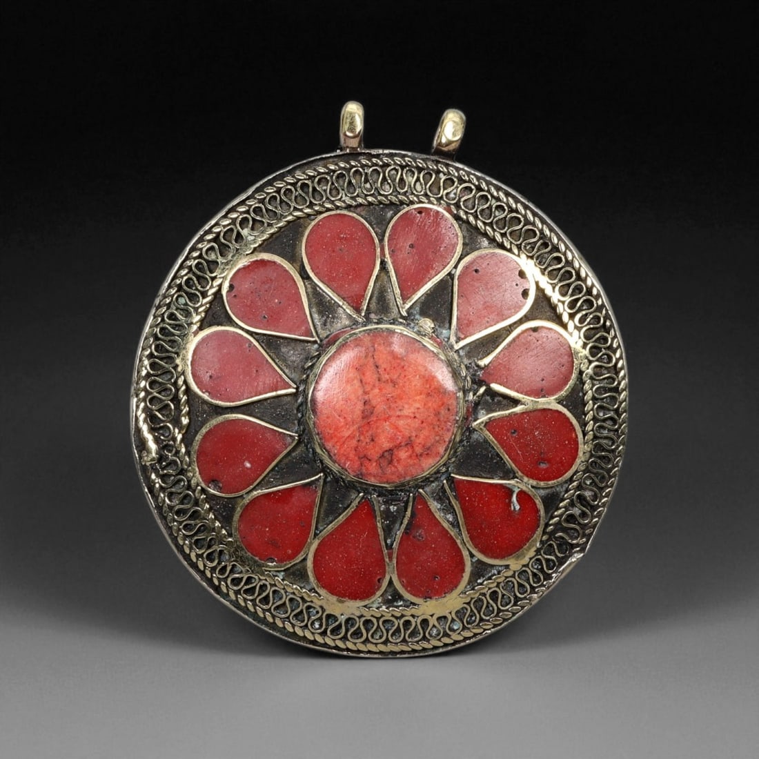 Vintage Himalayan Tribal Red Coral Brass Floral Pendant, 20th Century, 4cm: This radiant circular pendant captures the warmth and vitality of Himalayan tribal artistry through its bold floral design and rich red hue. The piece centers on a single round coral cabochon surround