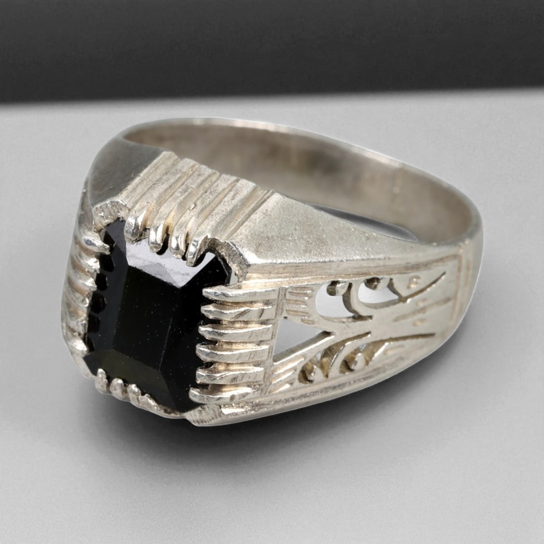 Antique Persian Revival Black Onyx Silver Filigree Ring, c. 19th-20th Century, US Size 8: This refined antique silver ring exemplifies the late Qajar-to-early Pahlavi era taste for bold masculine adornment inspired by Persian Revival aesthetics. The rectangular black onyx, cut in a step-fa