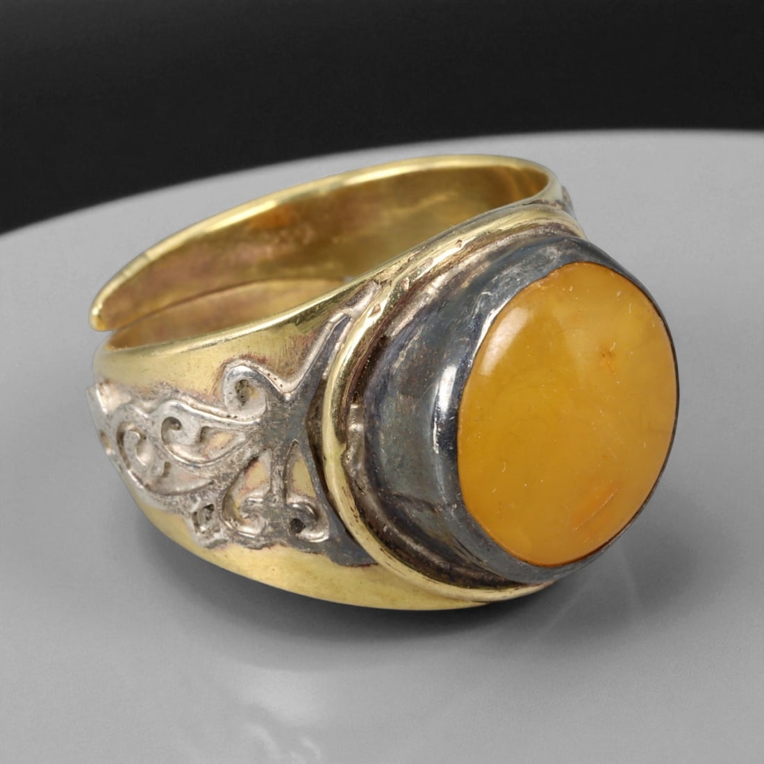 Vintage Himalayan Amber Cabochon Silver Gilt Ring, 20th Century: This bold Himalayan ring, crafted in the 20th century, is centered with a warm amber cabochon, its honey-golden hue glowing with natural inclusions and soft translucence. Set within a silver bezel and
