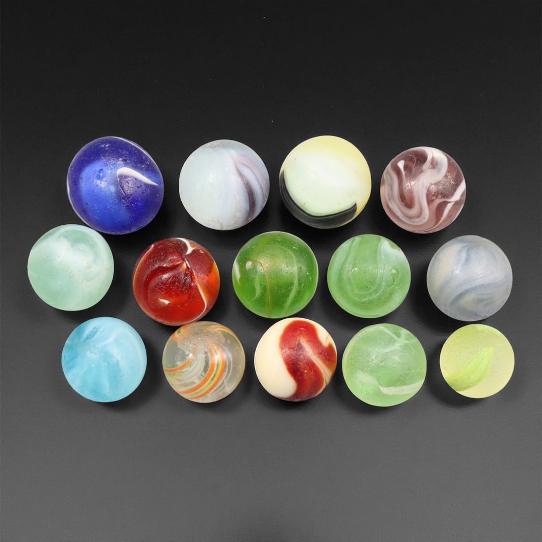 Vintage Glass Marbles Lot, Mid-20th Century, 1.3-1.7cm: This charming lot of vintage glass marbles, dating from the mid-20th century, reflects the artistry and playfulness of early handmade and molded glass craftsmanship. These marbles were produced during