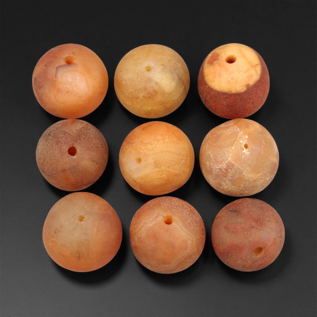 Antique Tibetan Carnelian and Agate Beads, c. 18th-19th Century, 1.8-2cm: This fine group of antique Tibetan beads, carved from carnelian and agate, dates to the 18th-19th century. Each spherical bead displays unique natural banding and earthy translucence, ranging in color