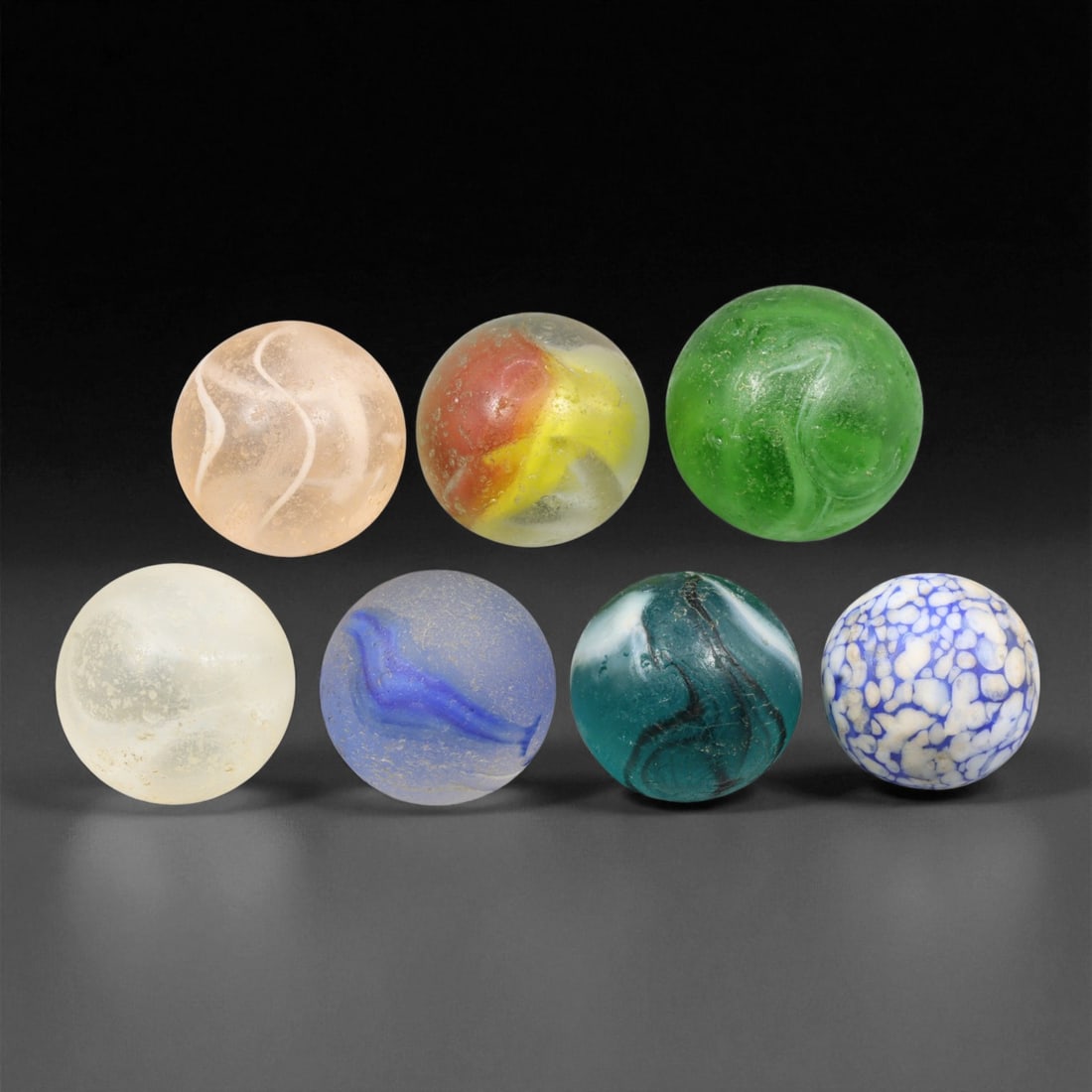 Vintage Glass Marbles Lot, Mid-20th Century, 2-2.5cm: This charming lot of vintage glass marbles, dating from the mid-20th century, reflects the artistry and playfulness of early handmade and molded glass craftsmanship. These marbles were produced during